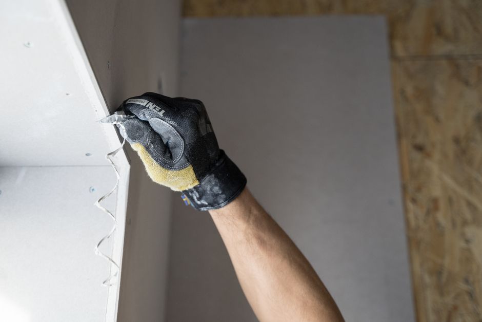 Close-up of a gloved hand applying plaster to a wall indoors in Falun, Sweden.