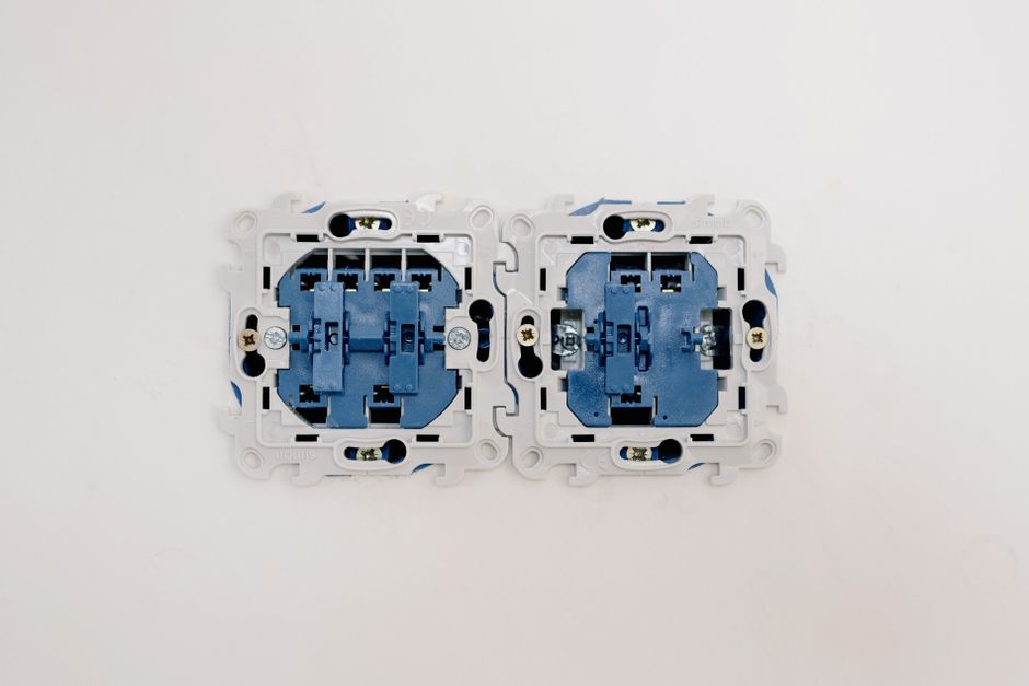 Opened electric switches without caps placed on light wall in apartment during repair works